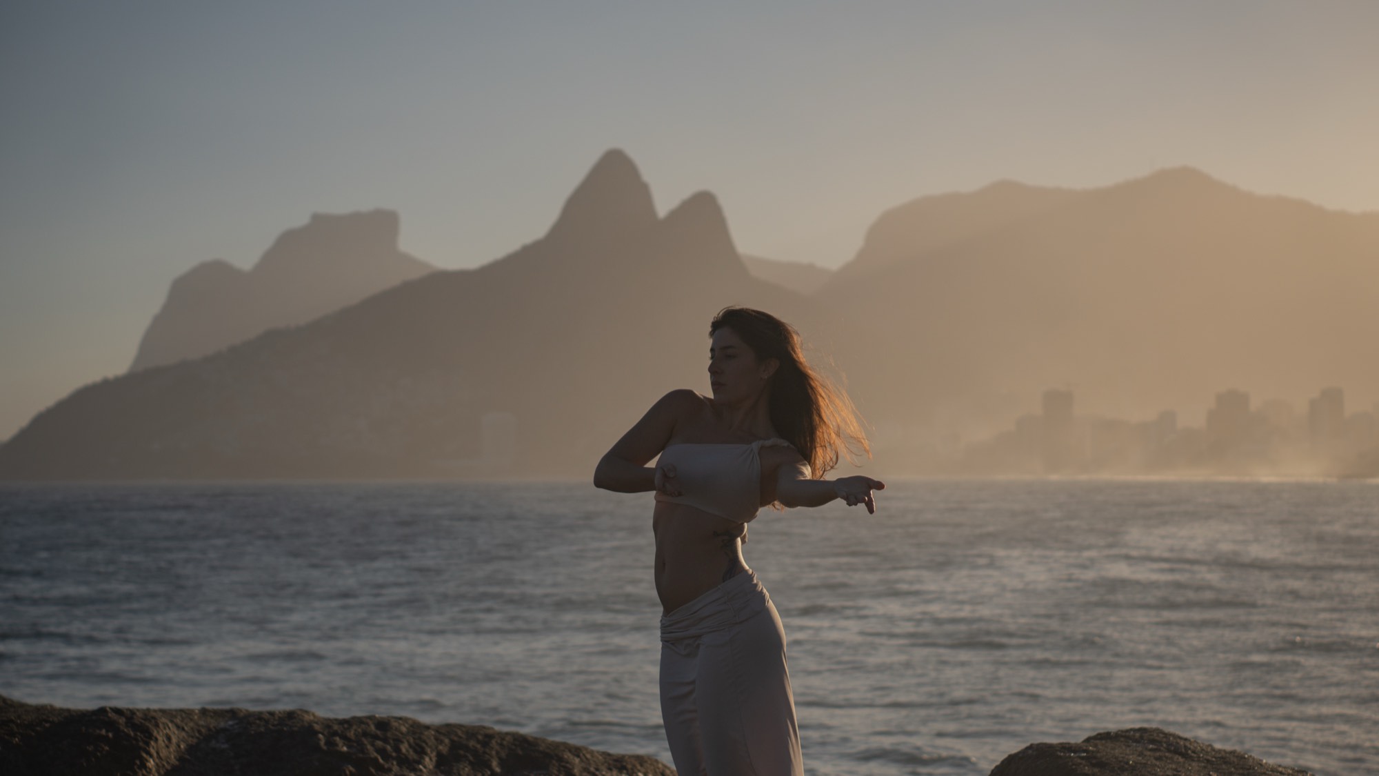 Gabriela em movimento à beira do mar, ao entardecer